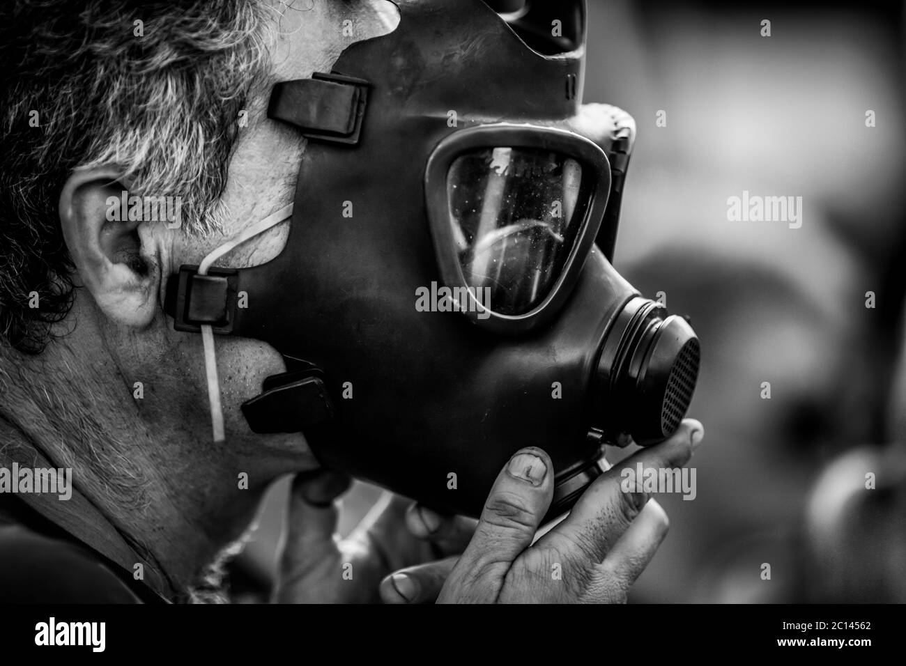 Artikeldetails mit einem Mann, der eine alte, alte, alte, militärische Gasmaske auf sein Gesicht legt - schwarz und weiß. Stockfoto