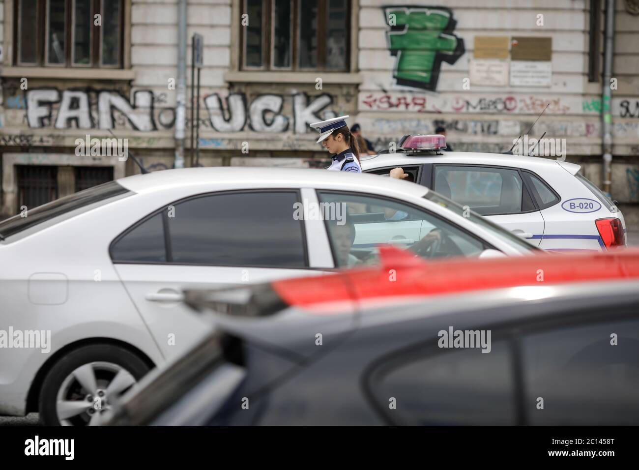 Bukarest, Rumänien - 13. Juni 2020: Rumänische Polizistin in der Nähe eines Polizeiwagens in der Innenstadt von Bukarest. Stockfoto