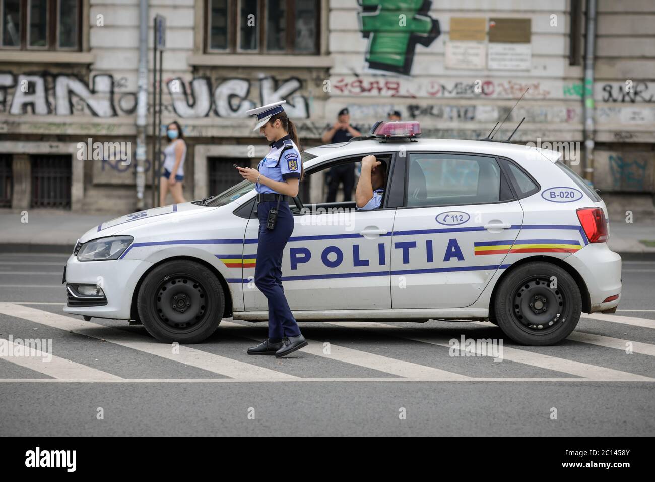 Bukarest, Rumänien - 13. Juni 2020: Rumänische Polizistin in der Nähe eines Polizeiwagens in der Innenstadt von Bukarest. Stockfoto