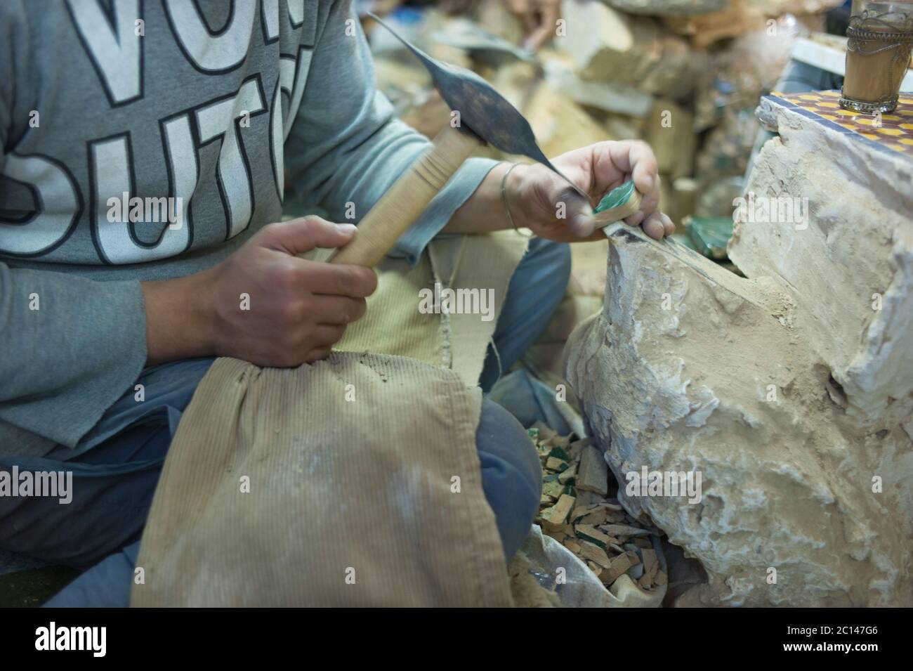 Morrocan Handwerker Schneiden von Keramikfliesen manuell mit schweren Hammer Stockfoto
