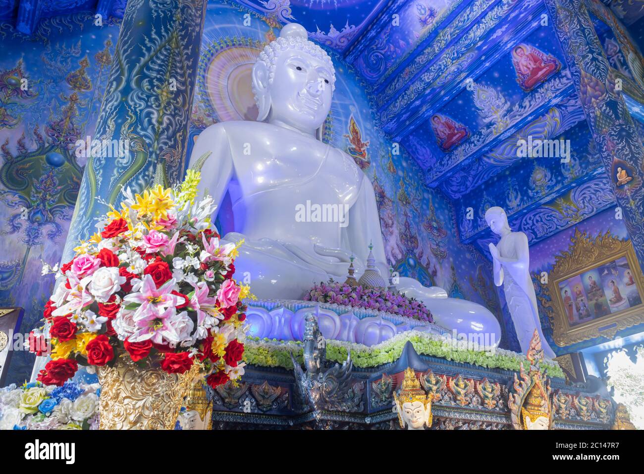 Chiangrai, Thailand - 7. Juni 2020: Weißer Buddha in Kirche und Gott sitzend und Thai Wandbild im Wat Rong Suea Ten oder Blauer Tempel auf der linken Seite Stockfoto