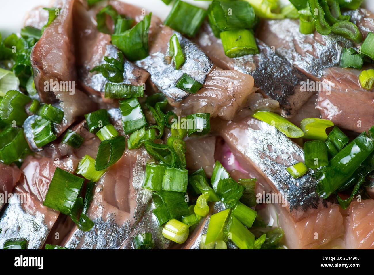 Hering mit Frühlingszwiebeln auf einer Platte geschnitten. Selektiven Fokus Makroaufnahme mit flachen DOF. Stockfoto