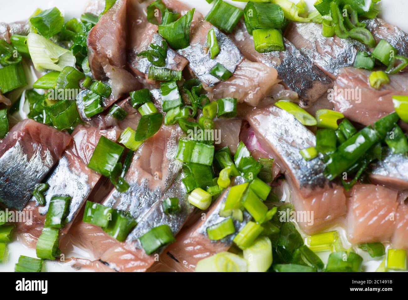 Hering mit Frühlingszwiebeln auf einer Platte geschnitten. Selektiven Fokus Makroaufnahme mit flachen DOF. Stockfoto