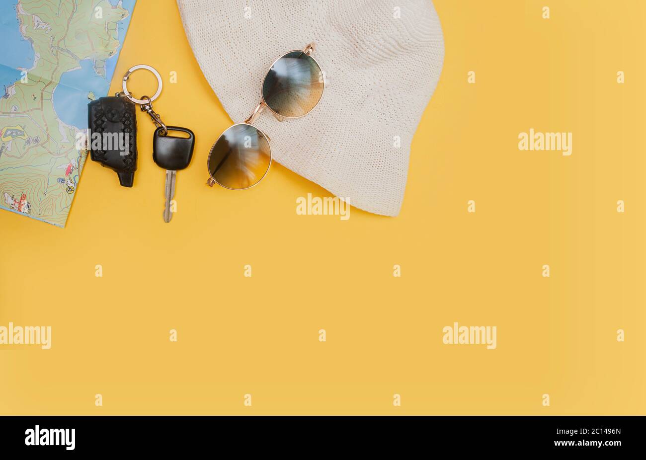 Autoschlüssel, Strickmütze, Sonnenbrille und Karte auf hellgelbem Hintergrund mit Platz für Text. Lokaler Tourismus mit dem Auto und inländische Autofahrten in der neuen Norm Stockfoto