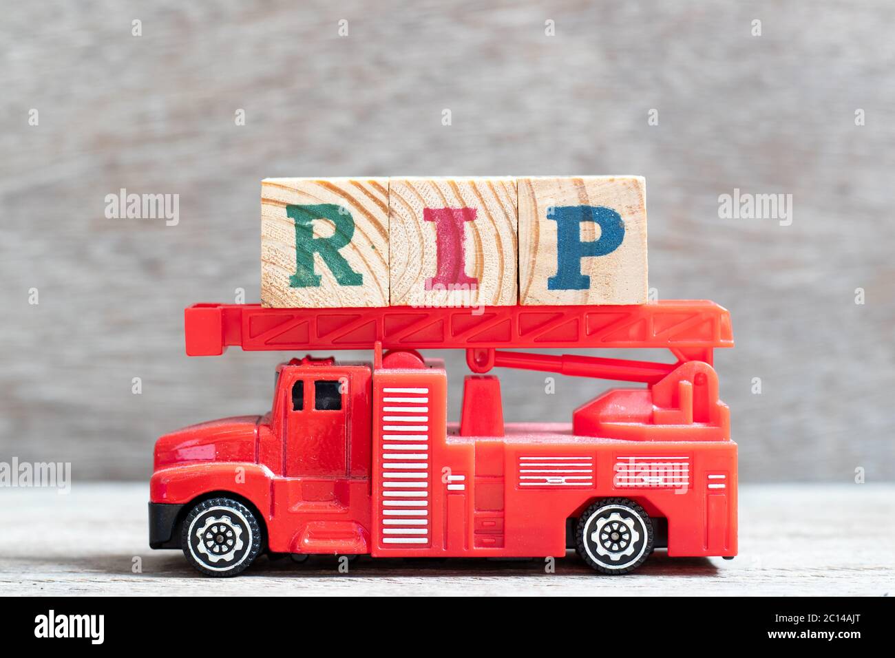 Rote Feuerwehrauto halten Buchstabenblock in Wort RIP (Abkürzung für Ruhe in Frieden) auf Holz-Hintergrund Stockfoto