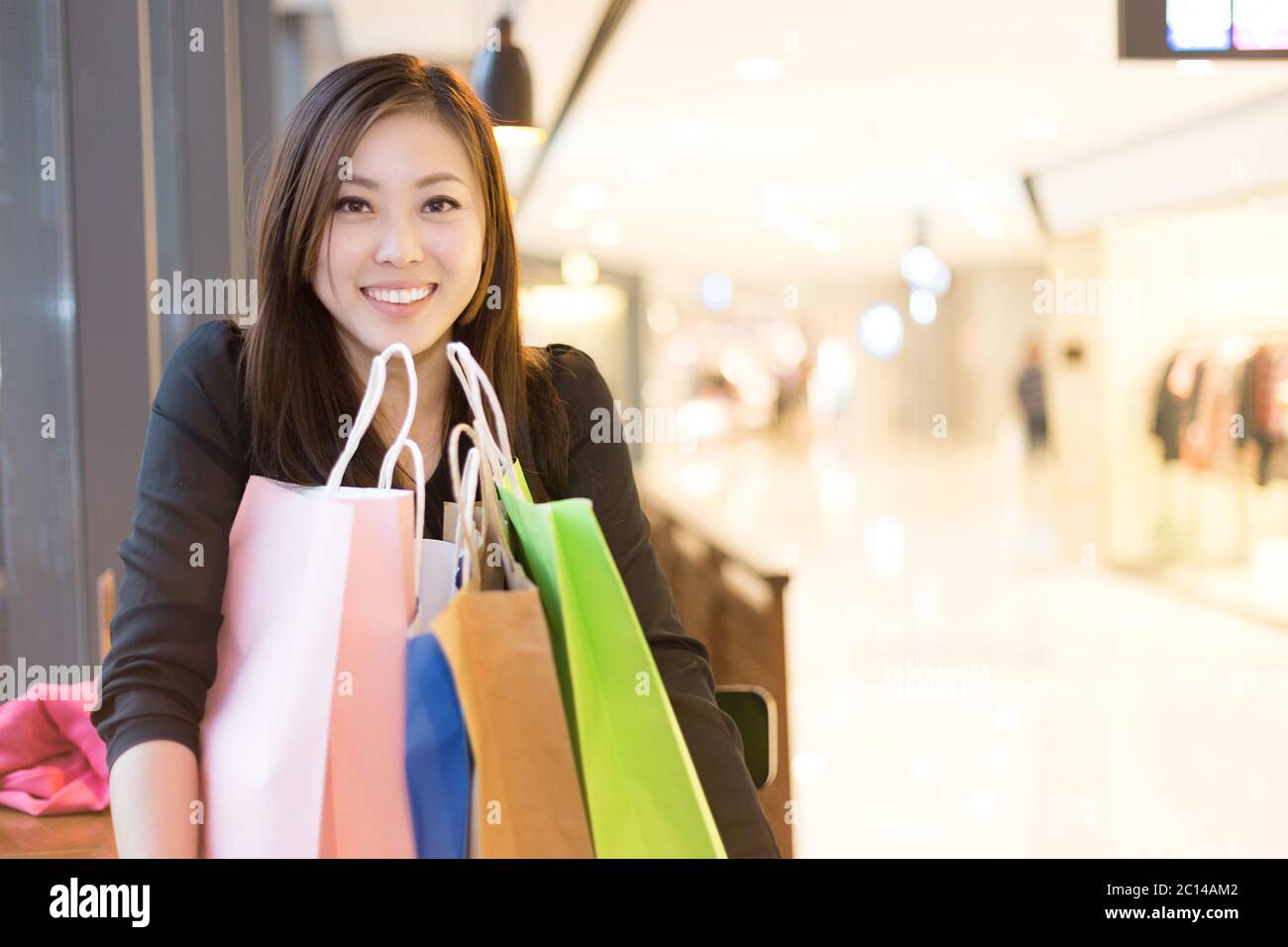 Junge asiatische Frau, die in einem modernen Einkaufszentrum einkaufen Stockfoto