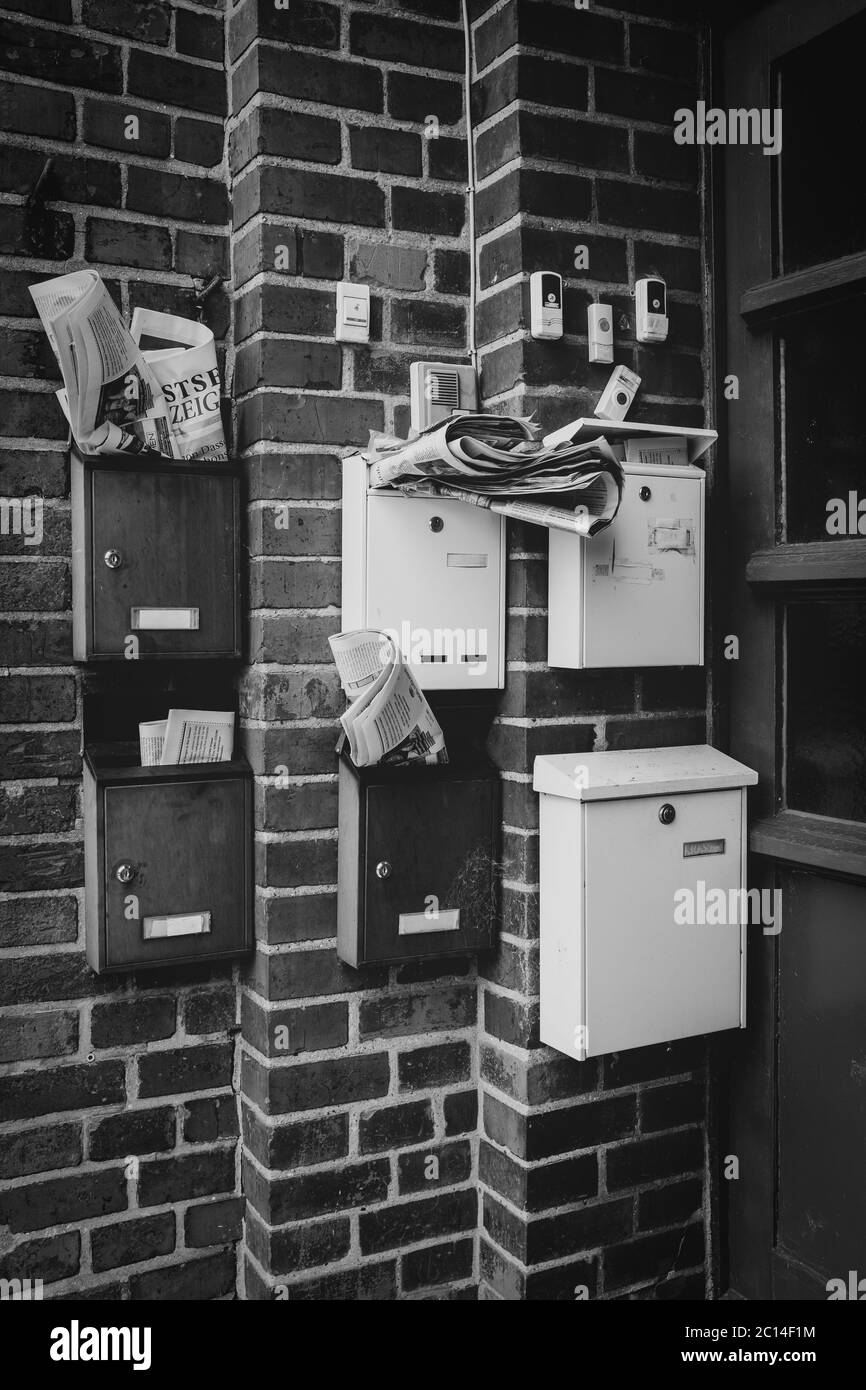 Sechs überfüllte Briefkästen hängen in einer Tür Stockfoto