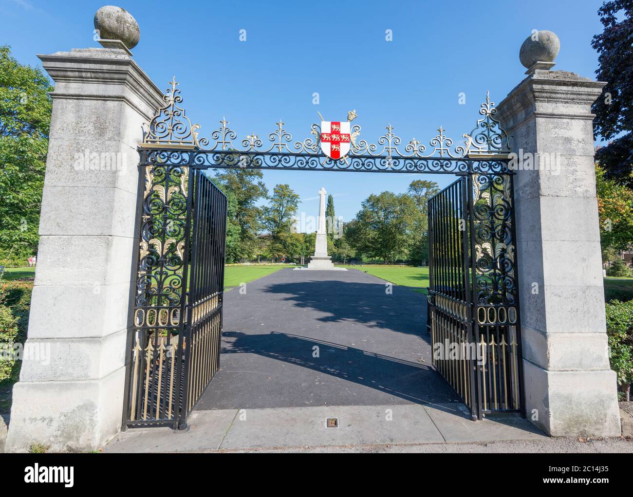 Die schmiedeeisernen Eingangstore und das Kriegs-Gedenkkreuz in den Memorial Gardens im Zentrum von York, North Yorkshire Stockfoto