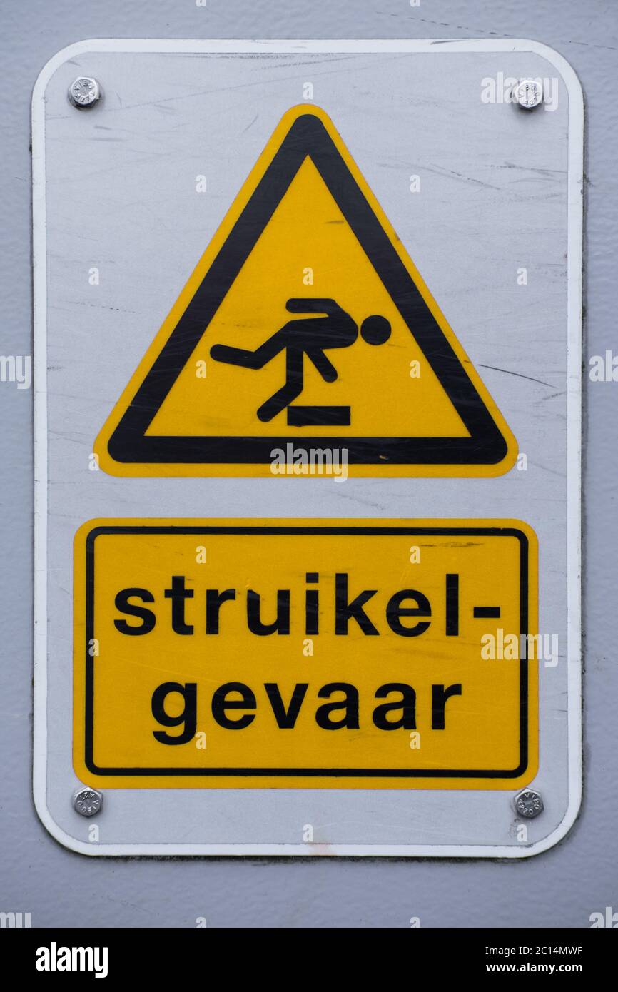 Schild 'Struikelgevaar' (Stolpergefahr), das warnt, dass es eine Schwelle auf dem Fußweg in den Niederlanden Stockfoto