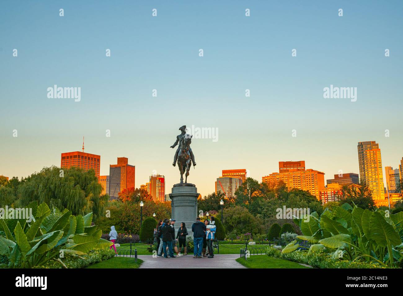 Boston USA - Oktober 13 2014; Stadtgebäude fangen die Nachmittagssonne hinter dem George Washington Monument, das vor einem blauen Himmel im Boston Public Garden liegt Stockfoto
