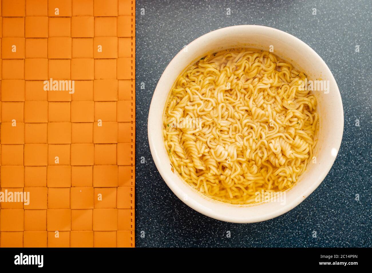 Instant Nudeln in Keramik-Schüssel auf orangefarbenem Hintergrund. Ist ein billiges, praktisches und einfaches Menü. Sparen Sie Geld während der weltweiten Finanzkrise Stockfoto