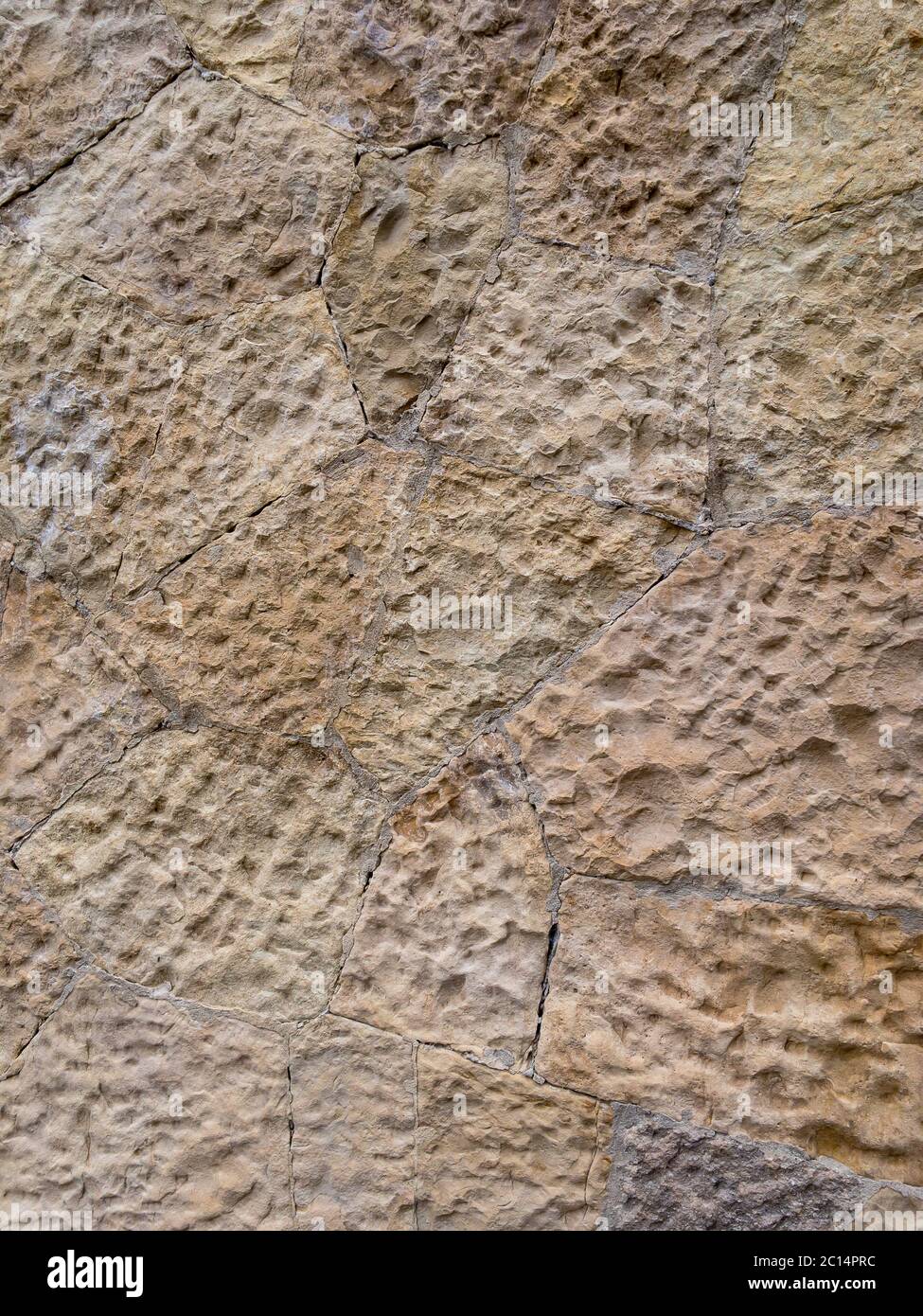 Braune Wand aus Steinblöcken von unregelmäßiger Form und unebene Oberfläche für den Einsatz als Hintergrund Nahaufnahme. Stockfoto
