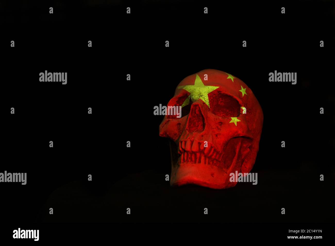 Ein weißer Schädel isoliert auf einem schlichten schwarzen Hintergrund mit der chinesischen Nationalflagge darüber. Stockfoto