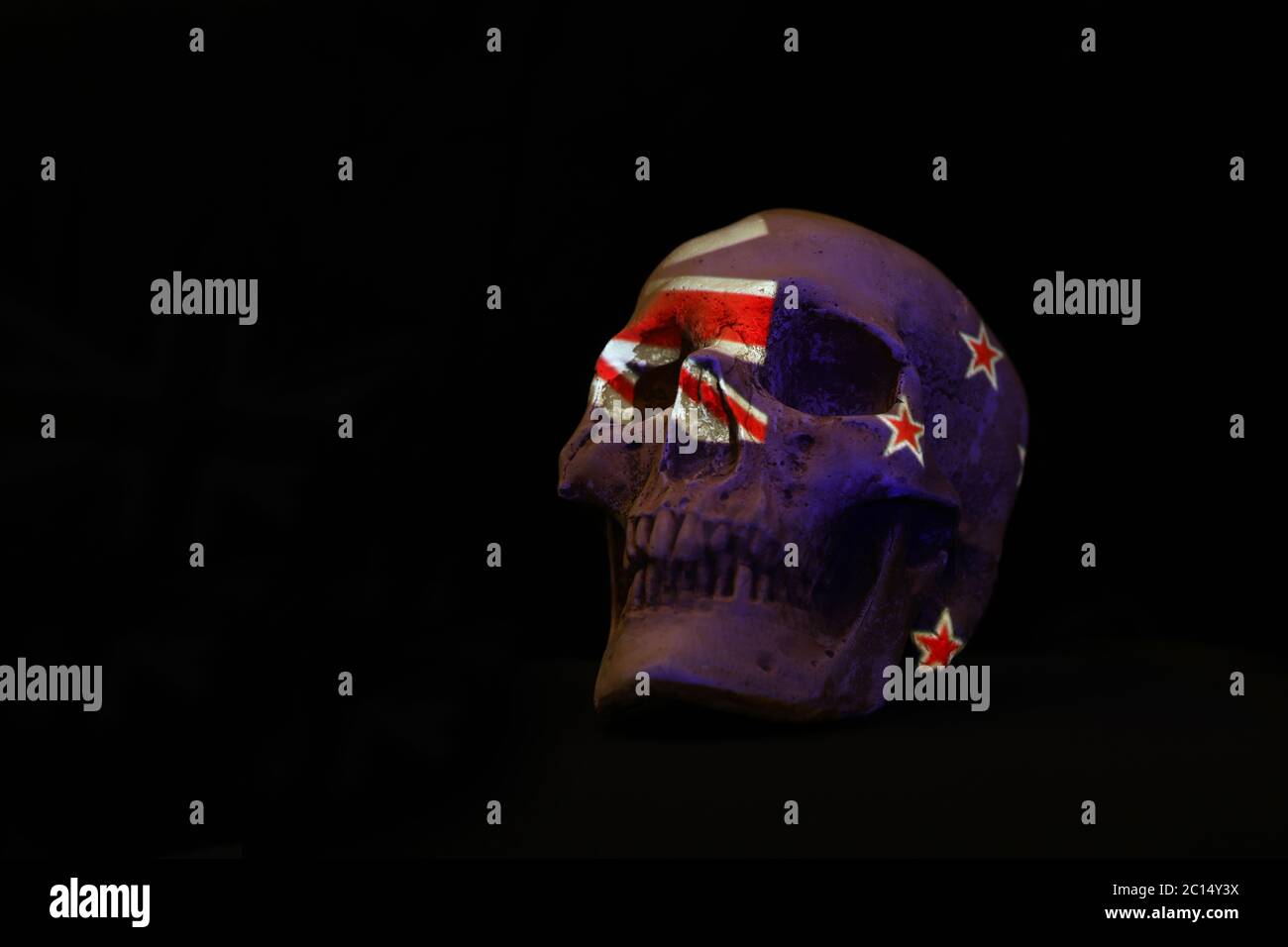Neuseeland Nationalflagge drapiert oder projiziert über einen weißen Schädel isoliert gegen einen schlichten schwarzen Backgorund. Stockfoto