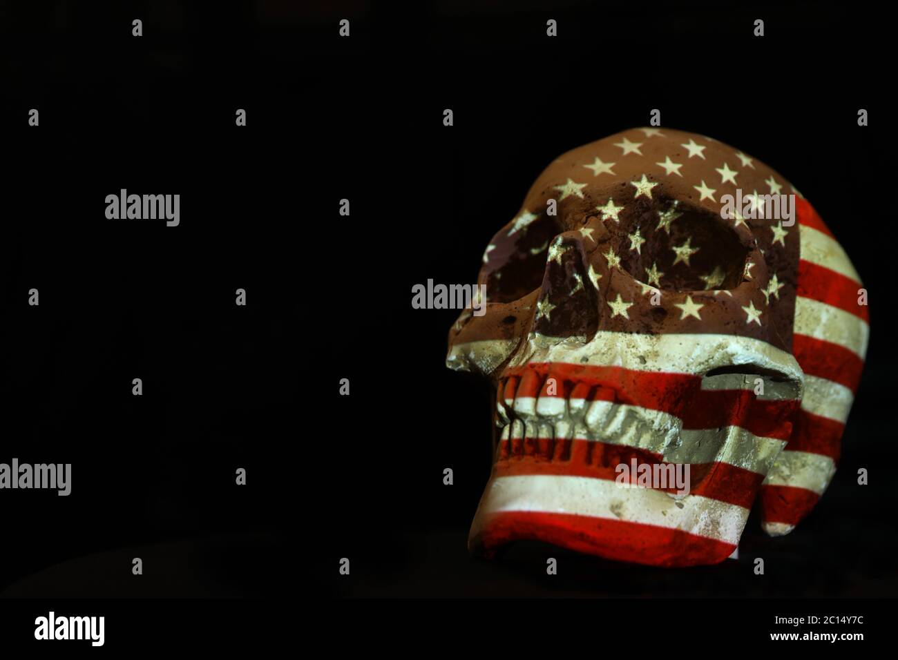 Isolierter weißer Schädel mit der amerikanischen Flagge der Vereinigten Staaten von Amerika, die darüber projiziert wird. Schlichter schwarzer Hintergrund. Covid-19 Corona-Virus oder Pistole Kontrolle Stockfoto