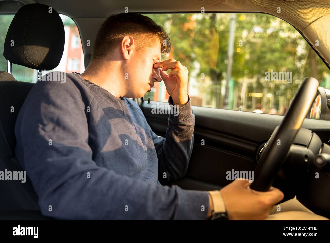 Junge kaukasische Fahrer einschlafen sitzen in ihrem Auto, reiben Augen, blieb stehen, um sich auszuruhen. Müde Mann Kopfschmerzen nach dem Fahren. Erschöpft, schlafen Stockfoto