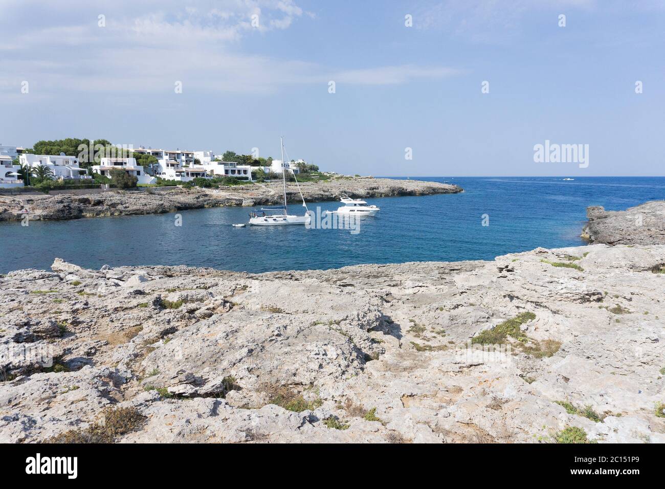 Panoramablick auf die mediterrane Küste mit einigen weißen Villen an der Küste, Felsen und blauem Himmel mit weißen Wolken. Mallorca. Balearen. Stockfoto