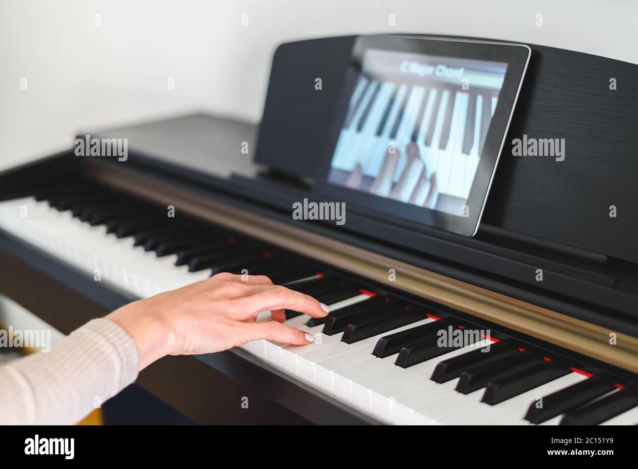 kaukasische Frau, die Klavier mit Videounterricht lernt. Konzept des virtuellen Lernens Stockfoto