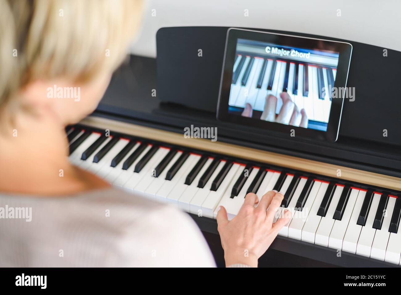 kaukasische Frau, die Klavier mit Videounterricht lernt. Konzept des virtuellen Lernens Stockfoto