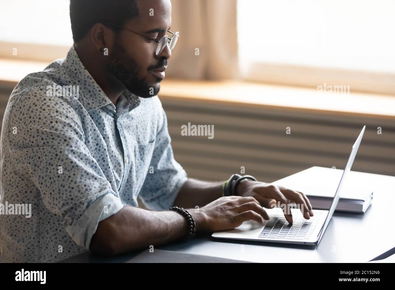 Fokussierter afrikanischer Geschäftsmann, der am Schreibtisch sitzt Stockfoto