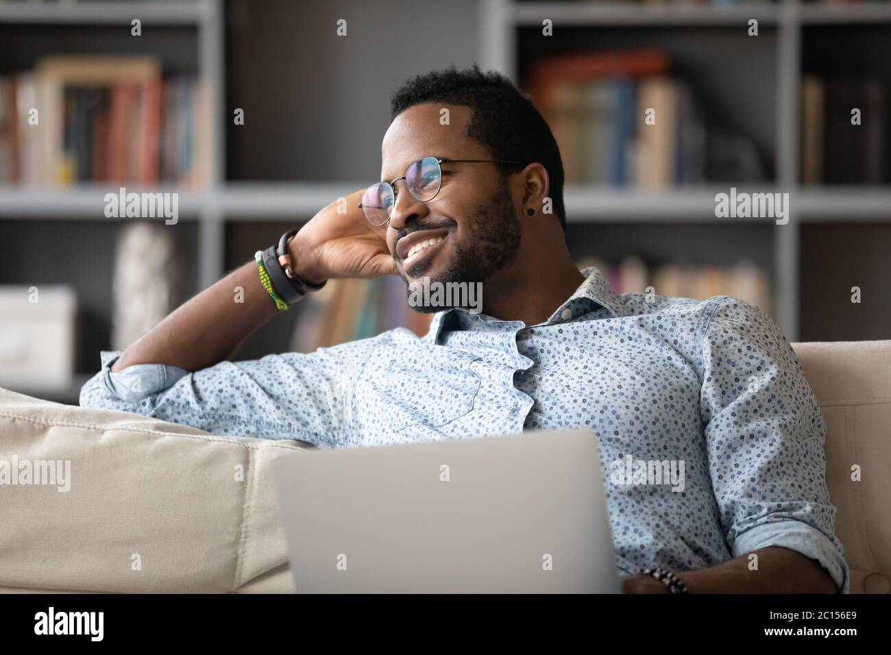 Afrikanischer Kerl abgelenkt mit Laptop Tagträume Blick auf Fenster Stockfoto
