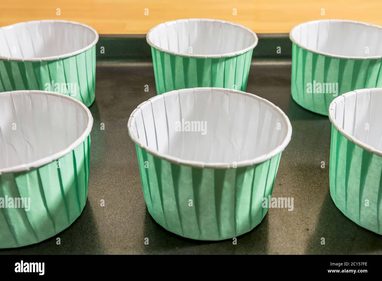 Cupcake-Hüllen auf einem Backblech bereit, mit Teig zum Backen im Ofen gefüllt Stockfoto