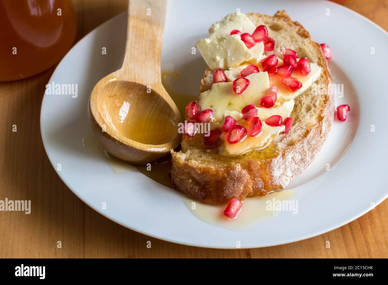 Scheibe Brot mit Käse, Granatapfel Samen und Honig auf Platte Nahaufnahme Stockfoto