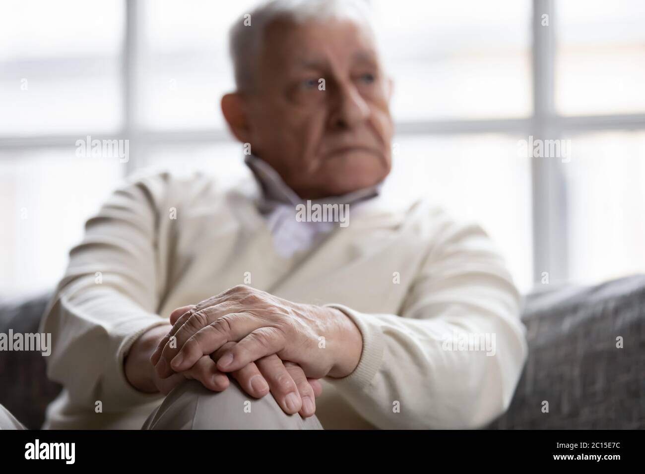 Nahaufnahme nachdenklicher älterer Mann, der mit gefalteten Händen sitzt Stockfoto