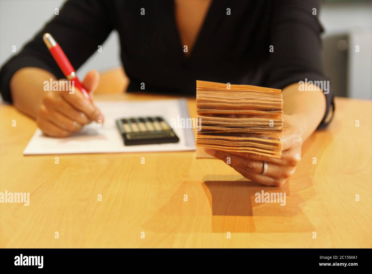 Frau, die an ihrem Schreibtisch arbeitete, linke Hand, die viele Banknoten hielt. Foto Stockfoto