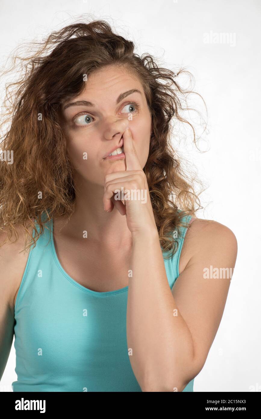 Schöne Brünette Mädchen Kommissionierung an ihrer Nase und ihr dummes Gesicht auf einem weißen Hintergrund Stockfoto