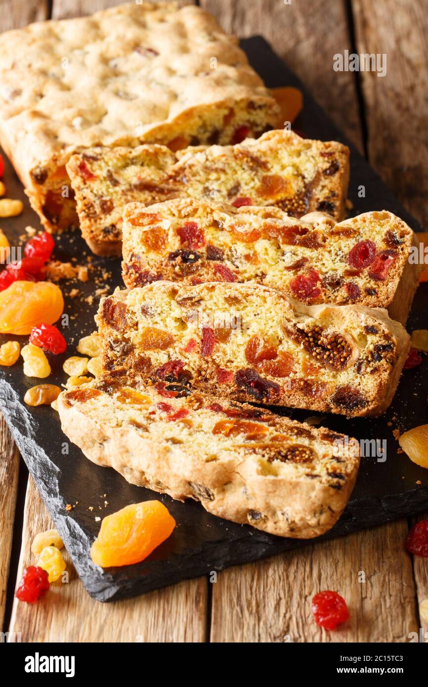 Festlicher Obstkuchen mit getrockneten Aprikosen Beeren Rosinen Feigen Kirschen Closeup auf einem Schiefertafel auf dem Tisch. Vertikal Stockfoto