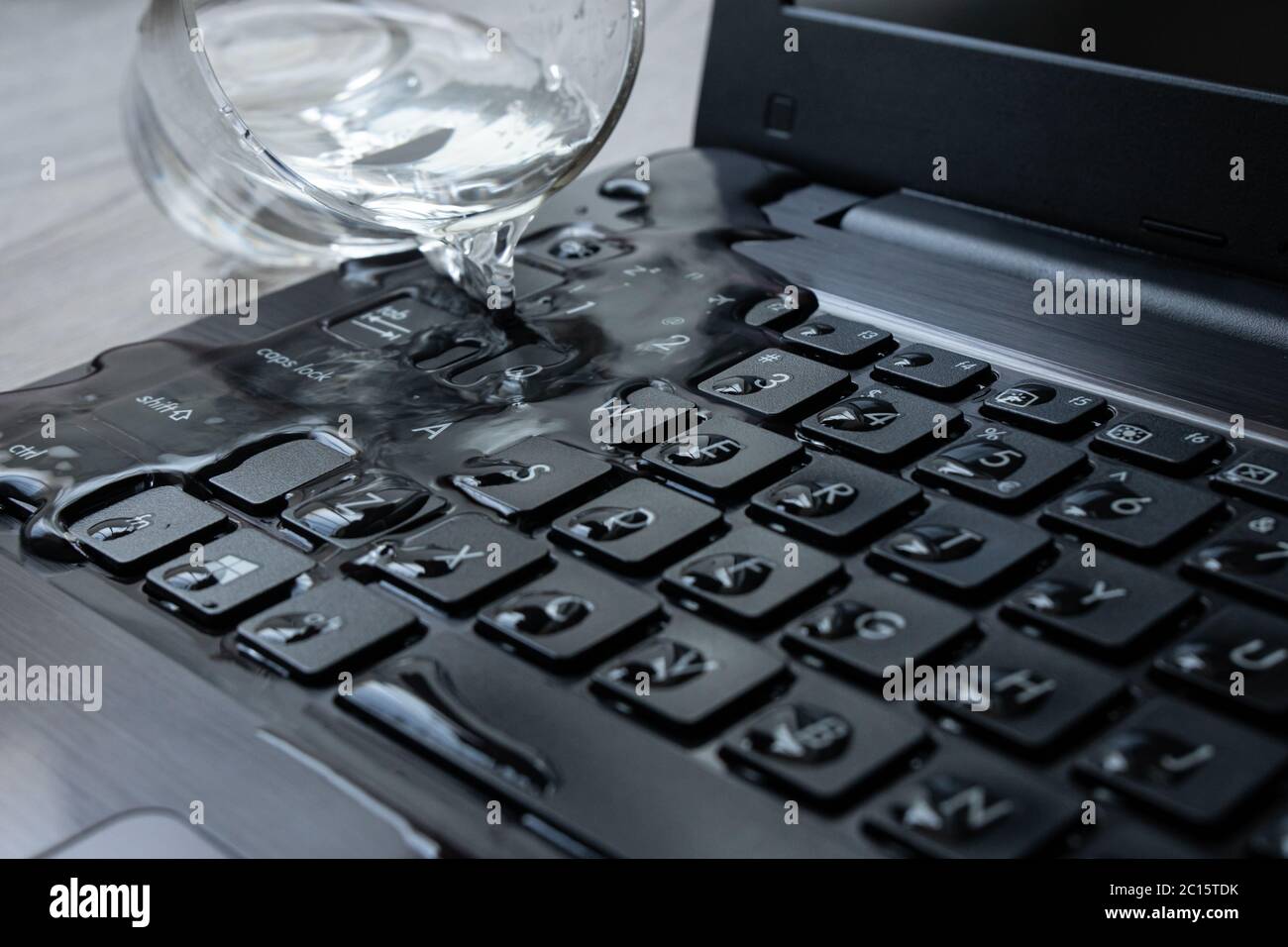 Wasser wird versehentlich über den Laptop verschüttet. Die Tastatur ist  voll mit Flüssigkeit und der Computer ist ruiniert Stockfotografie - Alamy