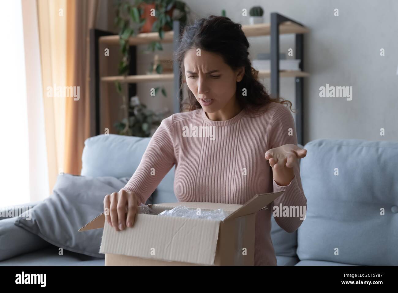 Verärgerte verwirrt Frau Auspacken Paket, falsch oder gebrochene Ordnung Stockfoto