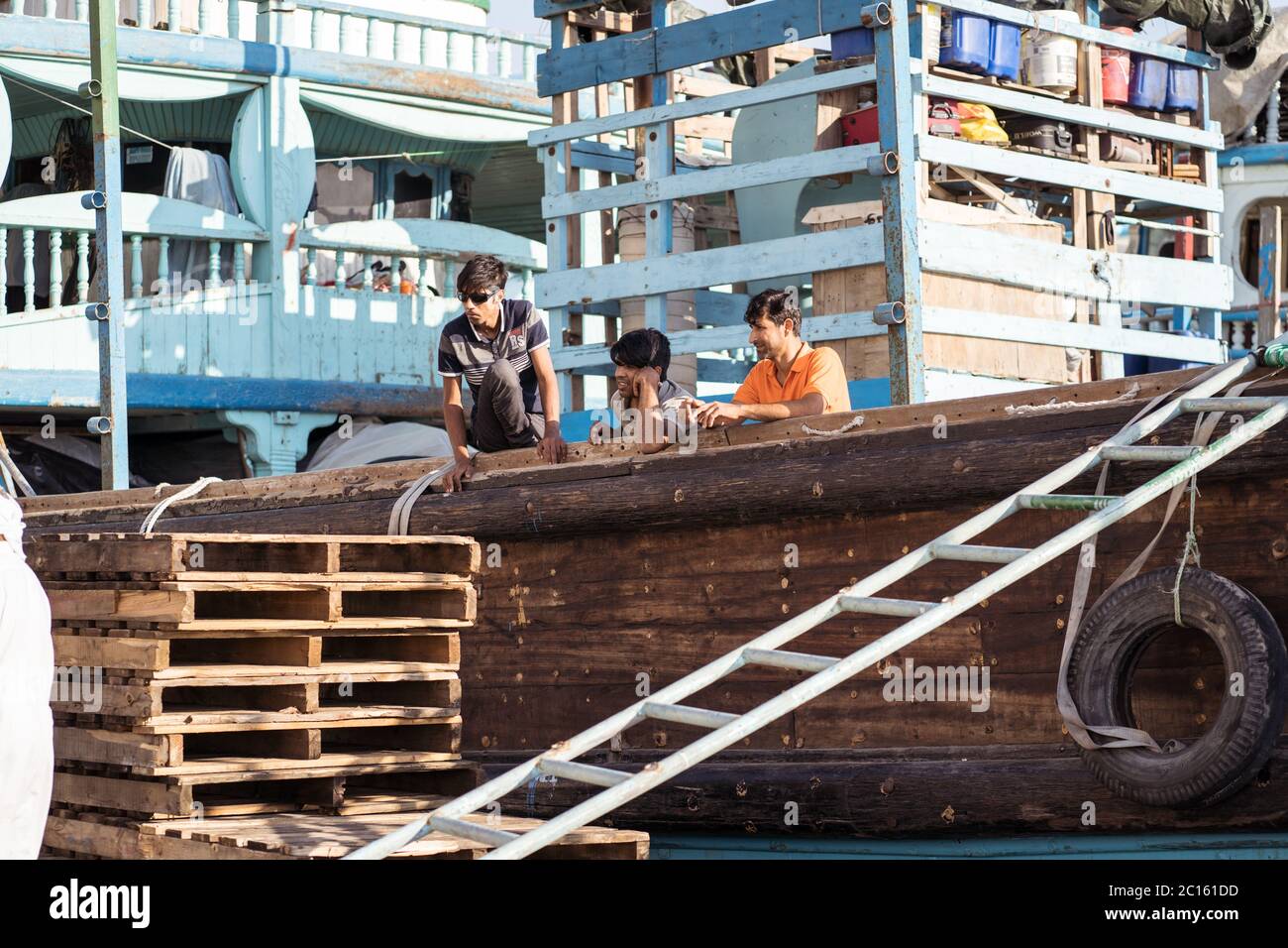 Dubai / Vereinigte Arabische Emirate - 1. Februar 2020: Wanderarbeiter arbeiten in traditionellen bunten Booten im Stadtzentrum von Dubai Hafen Stockfoto
