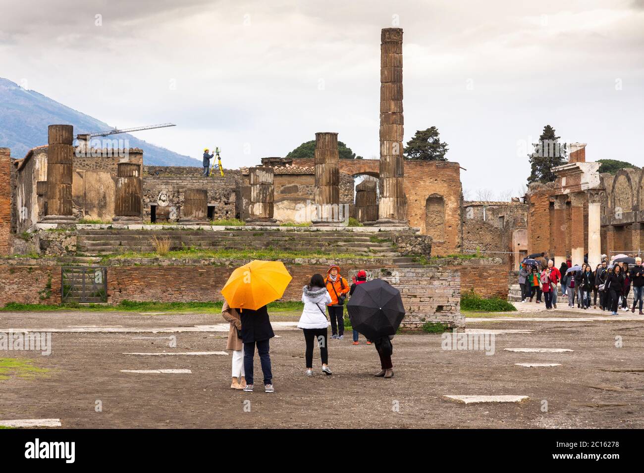 Touristen an einem regnerischen Tag im Forum Romanum (Foro Civile di Pompei) mit Blick auf den Jupiter-Tempel in der historischen Stadt Pompeji, Italien Stockfoto
