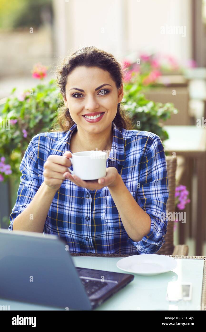 Junge lächelnde Frau woking auf Computer im Freien Stockfoto