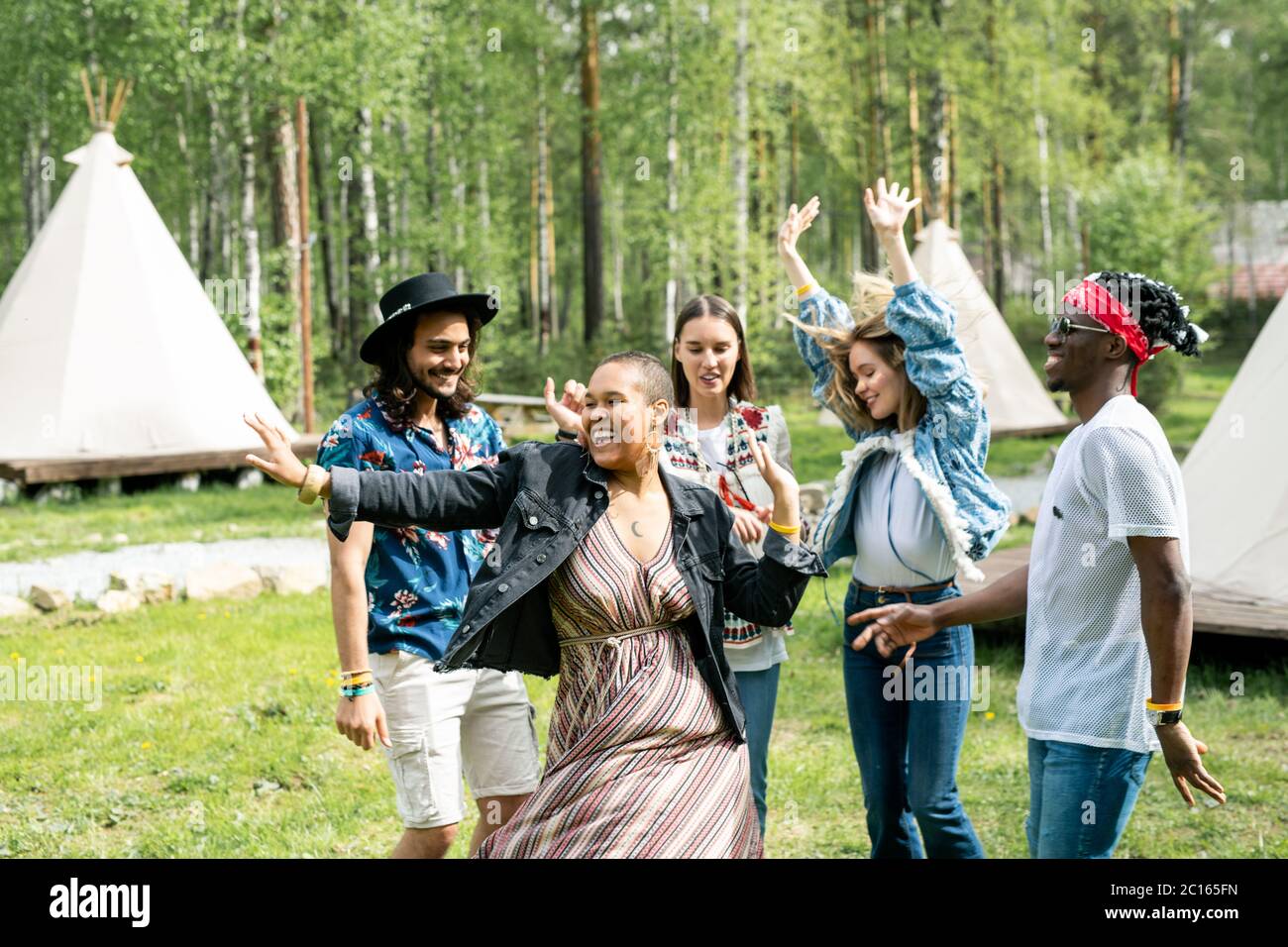 Energische junge multi-ethnische Menschen tanzen auf Musikfestival im Wald Stockfoto