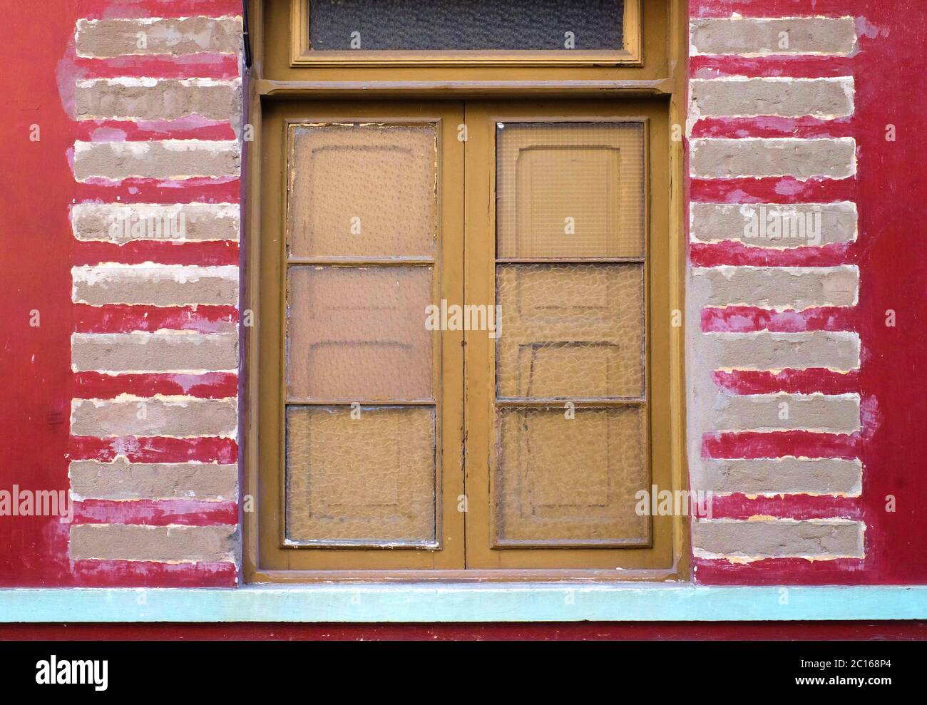 Fensterrahmen mit kaputtem Glas und roten Wandteilen, altes verfallenes und verlassene Hausdetails im Latino-Architekturstil. Stockfoto