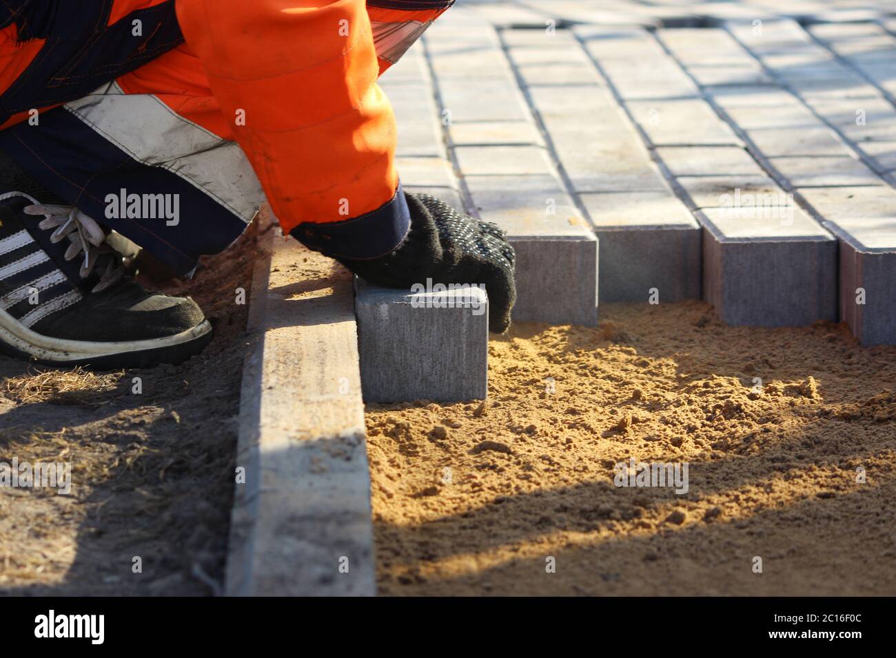 Reparatur des Gehwegs. Arbeiter Steinmetzen reparieren den Bürgersteig für das Verlegen Pflasterplatte. Stockfoto