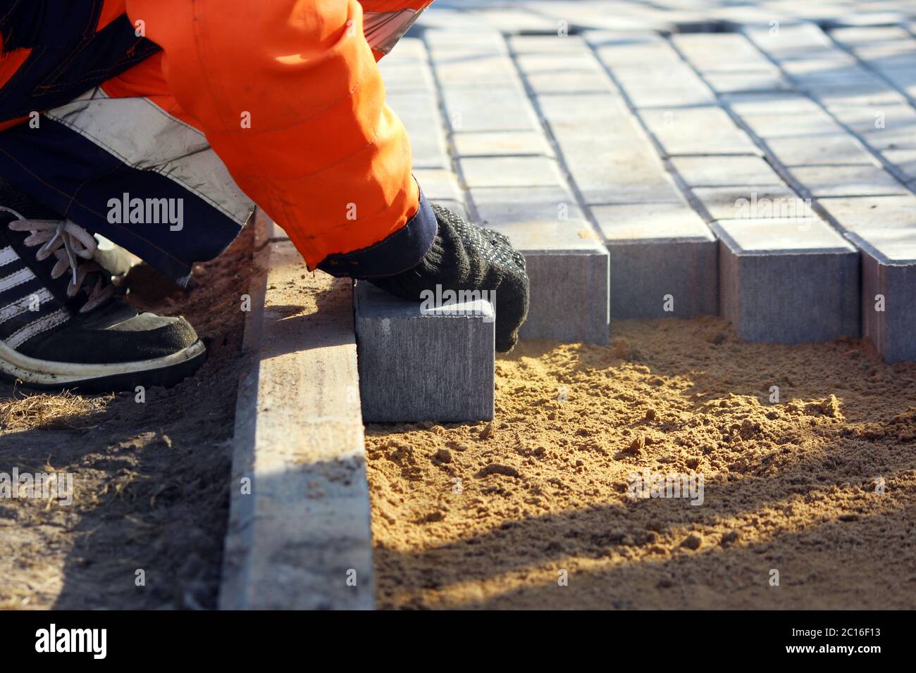 Reparatur des Gehwegs. Arbeiter Steinmetzen reparieren den Bürgersteig für das Verlegen Pflasterplatte. Stockfoto