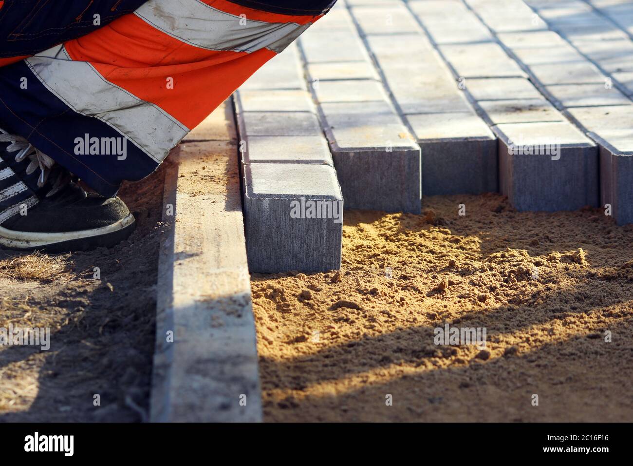 Reparatur des Gehwegs. Arbeiter Steinmetzen reparieren den Bürgersteig für das Verlegen Pflasterplatte. Stockfoto
