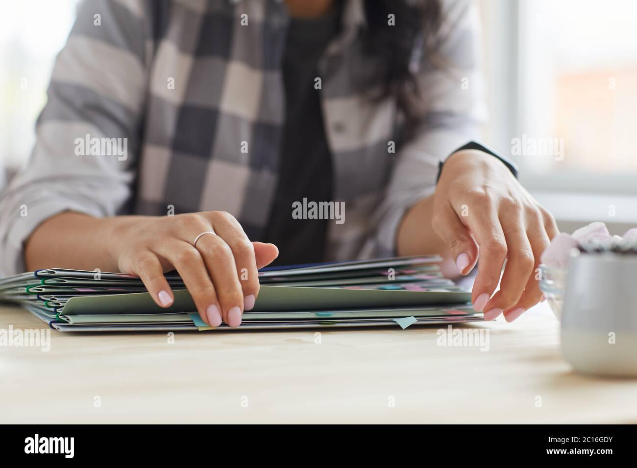 Nahaufnahme einer unerkennbaren jungen Frau, die Ordner mit Dokumenten öffnet, während sie im Home Office arbeitet, Kopierbereich Stockfoto