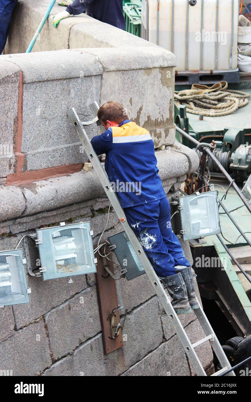Der Maurer repariert die Nahten zwischen den Granitplatten am Ufer des Flusses Fontanka in St. Petersburg Stockfoto