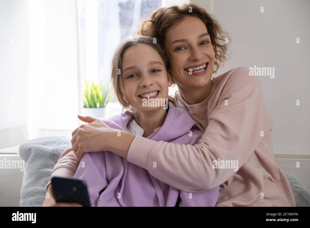 Portrait von glücklich Mutter und teen Tochter Umarmung zu Hause Stockfoto