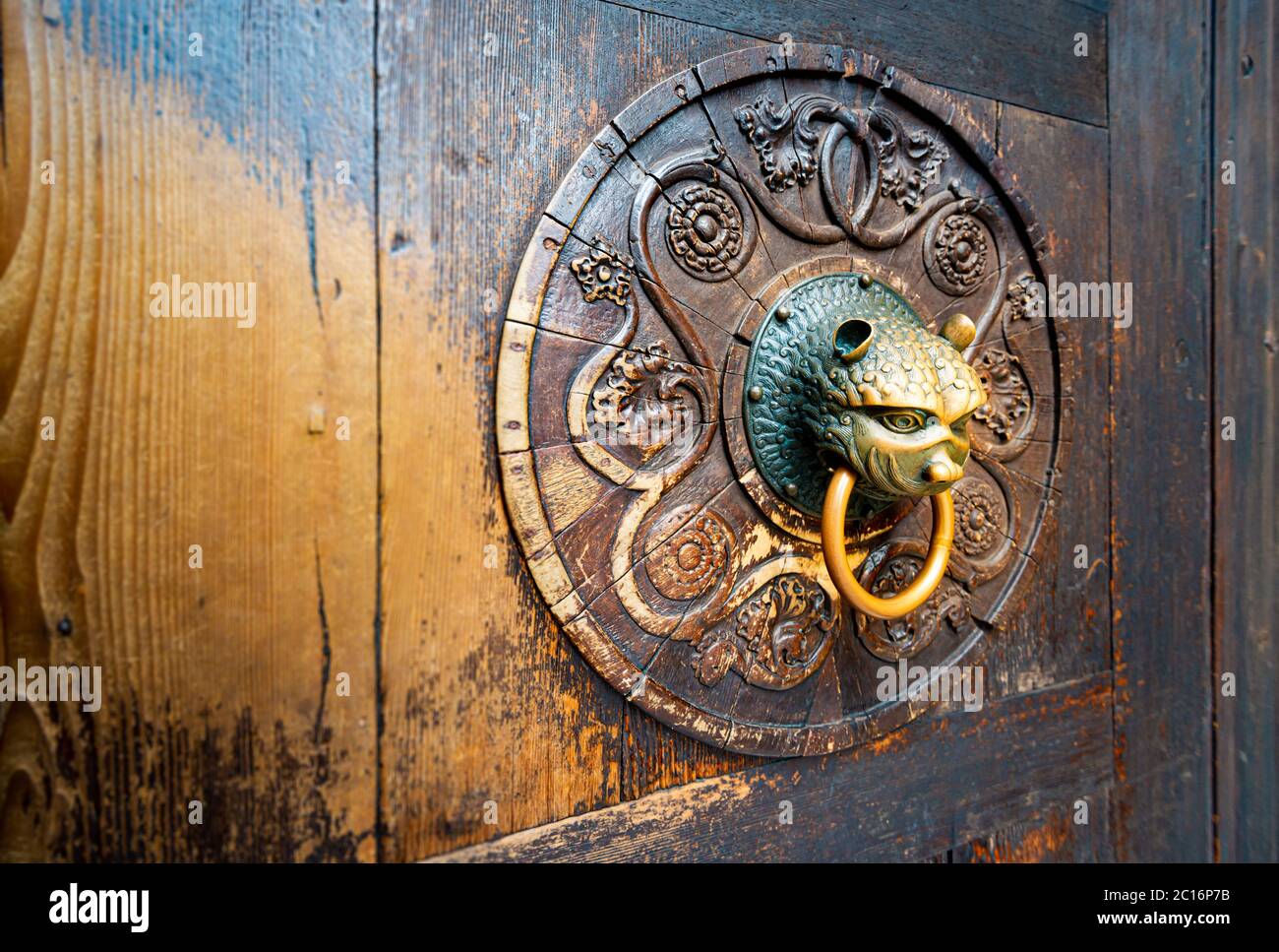 Detail der alten Holztür mit Metallgriff an Bord mit geschnitztem Muster. Dunkelbraune massive Eingangstür im Vintage- und Antikstil. Außen und Facad Stockfoto