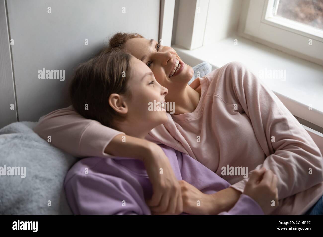 Glückliche Mutter und Tochter im Teenageralter entspannen sich im Bett zusammen Stockfoto