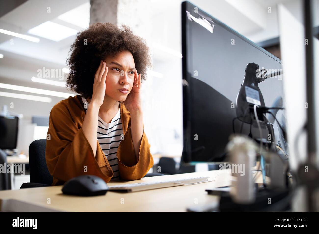 Überarbeitet und frustrierte junge Frau vor der Computer im Büro Stockfoto