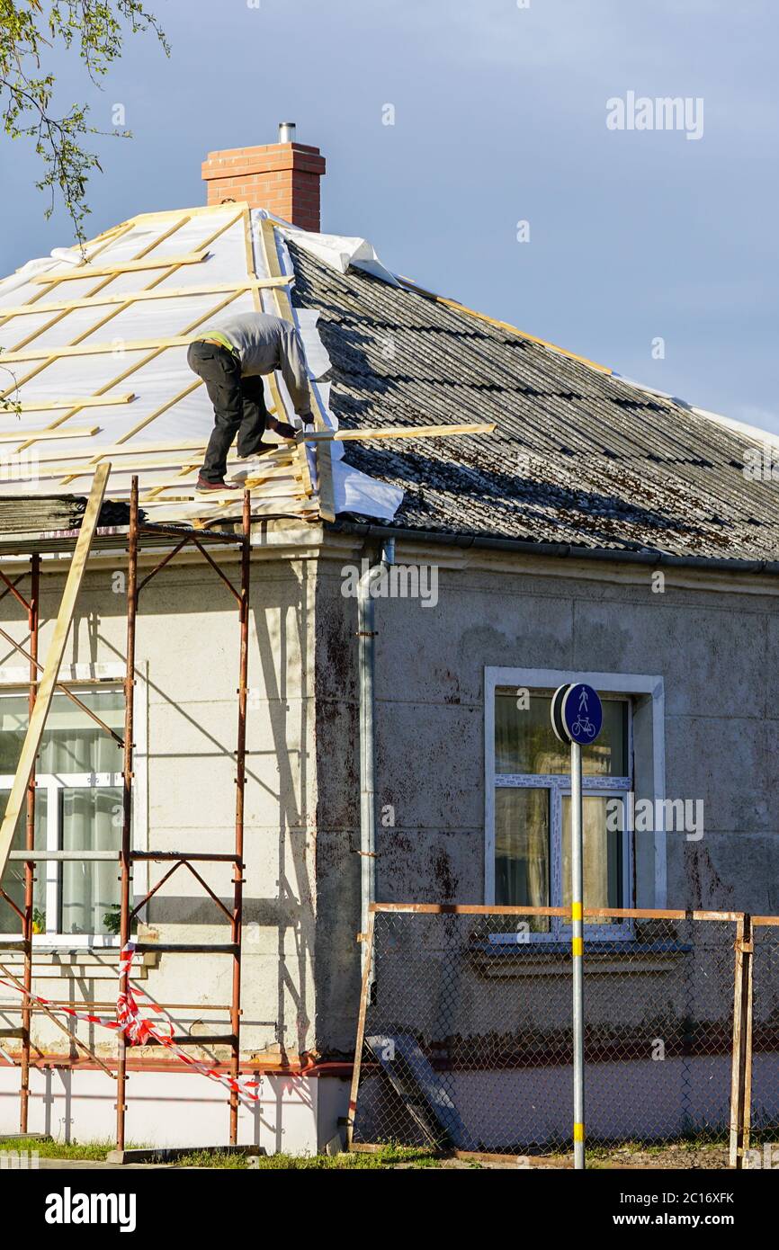 Gefährliche Arbeiten auf dem Dach des Hauses ohne Arbeitsschutzausrüstung Stockfoto