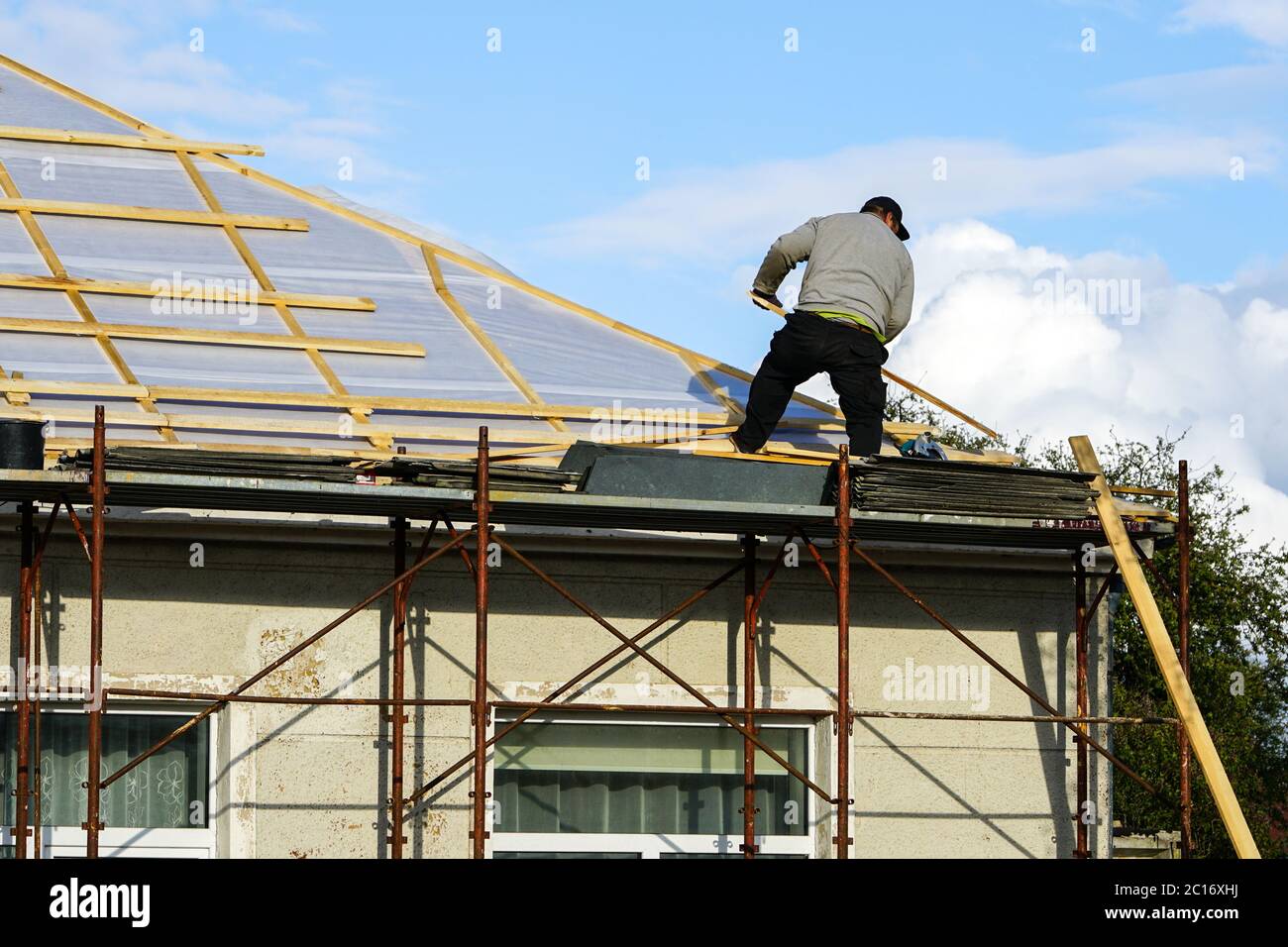 Gefährliche Arbeiten auf dem Dach des Hauses ohne Arbeitsschutzausrüstung Stockfoto