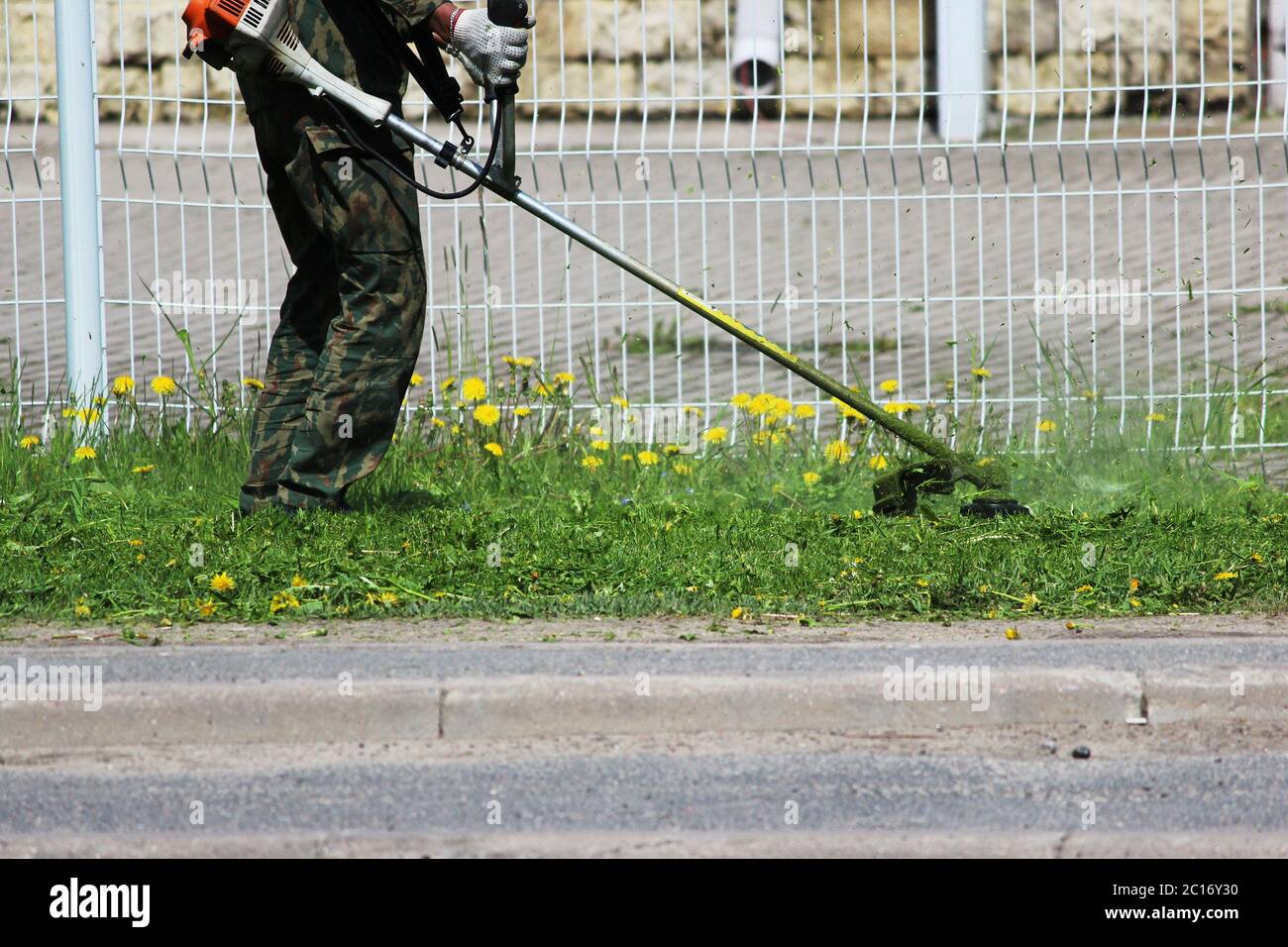 Arbeitnehmer mit einem Beschneidemaschine Rasenmähen. Stockfoto